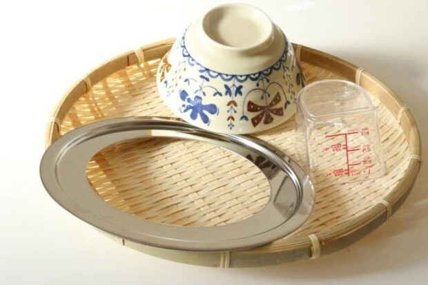 竹ざるの上に置かれた茶碗と計量カップとステンレス製の楕円皿 竹ざるの上に置かれた茶碗と計量カップとステンレス製の楕円皿