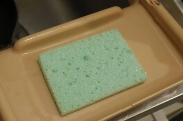 ベージュ色のスポンジホルダーに置かれた緑色のスポンジ ベージュ色のスポンジホルダーに置かれた緑色のスポンジ