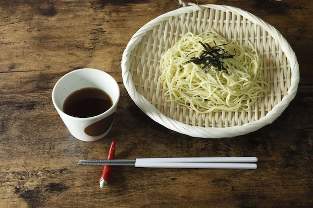 盆ざるに盛り付けられた冷やし中華と、つゆ、箸が並ぶ食卓