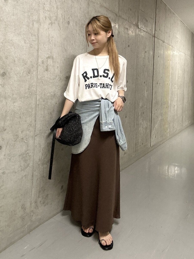 ロゴTとブラウンロングスカート、デニムシャツを巻いた女性 ロゴTとブラウンロングスカート、デニムシャツを巻いた女性