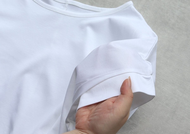 白いTシャツの袖口を指でつまみ生地の厚みを見せている