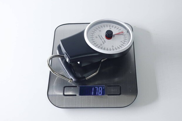 デジタルスケールの上に置かれたスーツケース用計り。スケールには178gと表示。