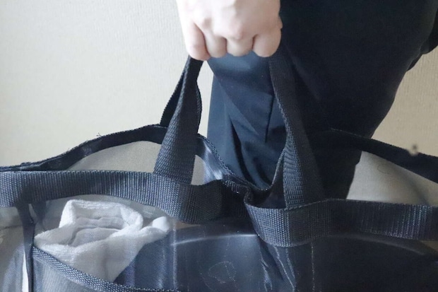 女性が黒いメッシュトートバッグの持ち手を掴んでいる 女性が黒いメッシュトートバッグの持ち手を掴んでいる
