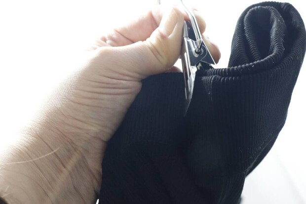 手でダイソーのフックピンチを使い、黒い衣類を挟んでいる様子 手でダイソーのフックピンチを使い、黒い衣類を挟んでいる様子