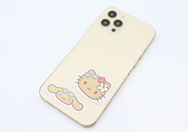 スマートフォンの背面にキティとシナモロールのステッカーが貼られている スマートフォンの背面にキティとシナモロールのステッカーが貼られている