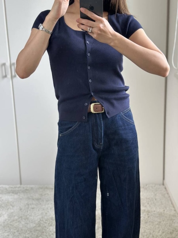 ネイビーのカーディガンとワイドデニムを着用した女性が鏡越しに全身を撮影