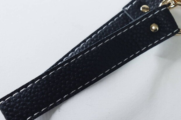 黒い合皮素材のスマホストラップのシボ感と白いステッチ 黒い合皮素材のスマホストラップのシボ感と白いステッチ