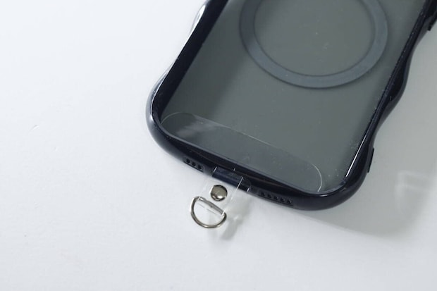黒いスマホケースの充電口に透明なストラップシートを挟み込んだ状態