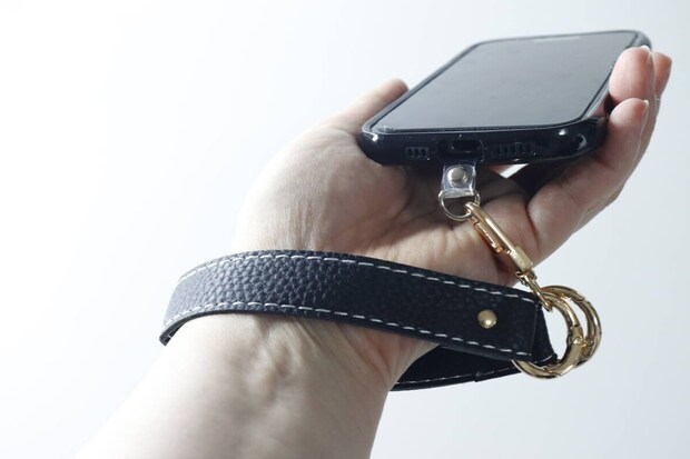 女性が黒いスマホストラップを手首に通してスマホを持っている様子