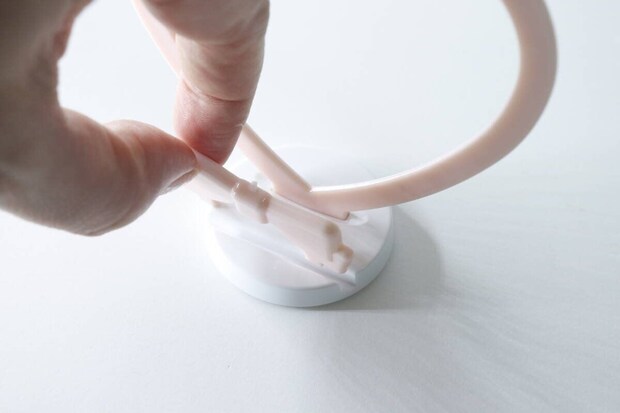 白い台座にピンクのハート型スタンドを差し込んで組み立てる手元