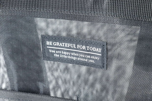 バッグの前面に縫い付けられた「BE GRATEFUL FOR TODAY」の英字ロゴ