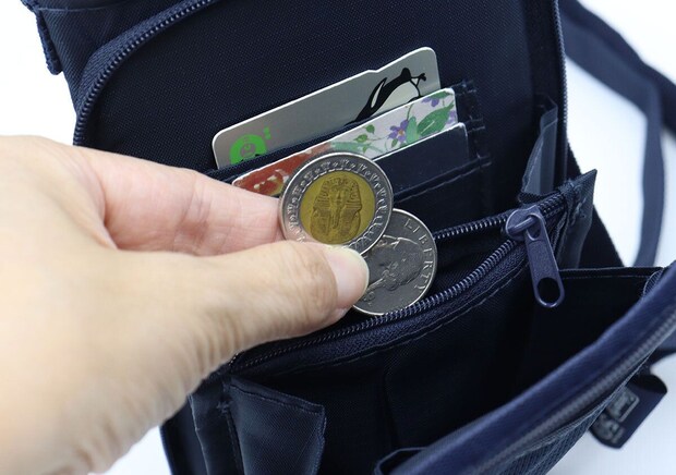 お財布機能の小銭入れにコインを入れる手 お財布機能の小銭入れにコインを入れる手