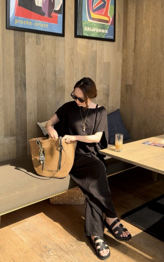 カフェのベンチに座りバッグの中を見る黒い服の女性