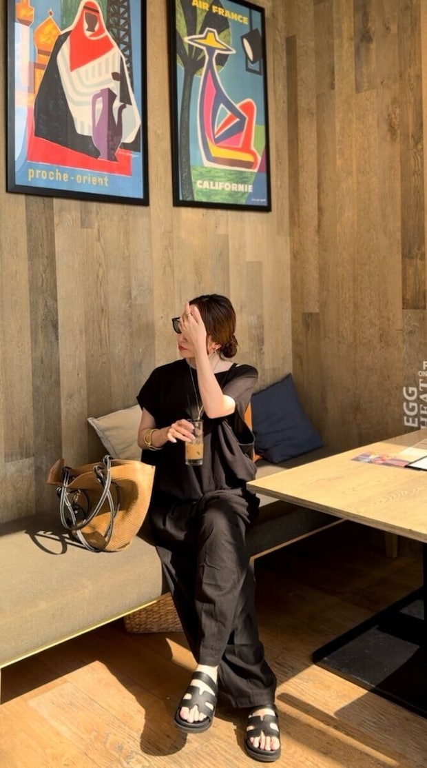 カフェのベンチでアイスコーヒーを飲む黒い服の女性