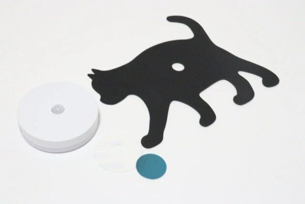 白い円形のライト本体と黒い猫のシルエットプレート、丸いシールが写っている