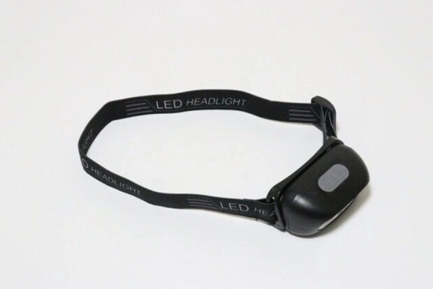 白い背景に置かれた黒いヘッドライト。バンド部分に「LED HEADLIGHT」の文字 白い背景に置かれた黒いヘッドライト。バンド部分に「LED HEADLIGHT」の文字