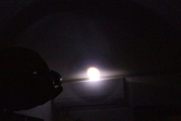 暗い部屋で懐中電灯の光が一点を強く照らしている様子