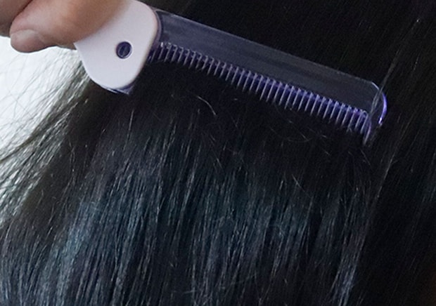 ダイソーの折りたたみコームで黒髪をとかしている様子
