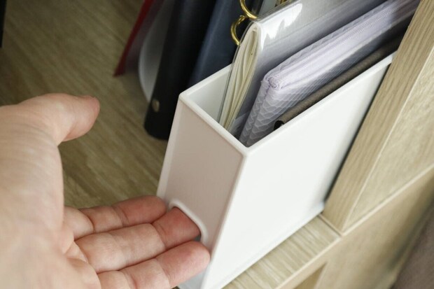 棚に置かれた収納ボックスから手帳を取り出す女性の手