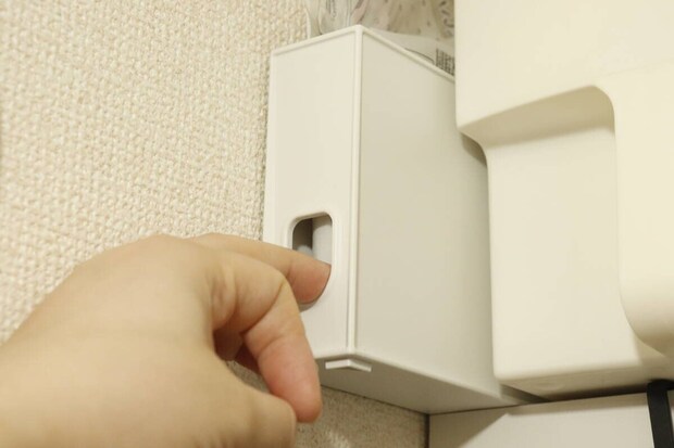 吊り戸棚に設置された収納ボックスの下側指穴に指を入れる
