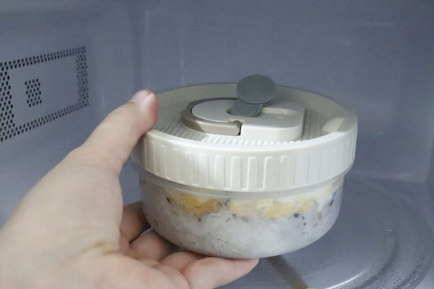 電子レンジにハンドル付弁当箱を入れようとする手