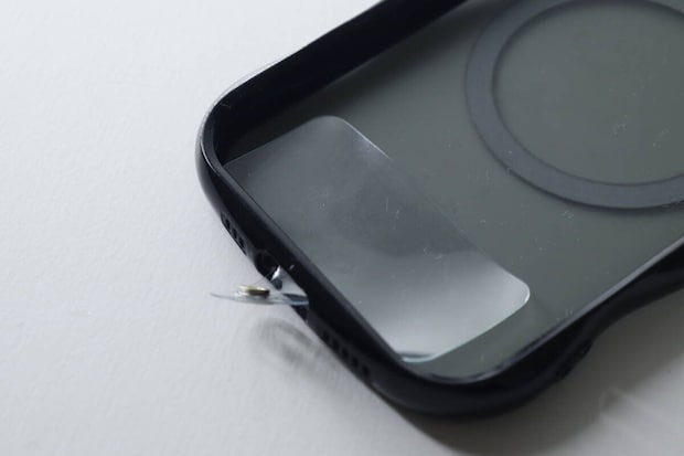 黒いスマホケースに透明なストラップホルダーを挟む様子 黒いスマホケースに透明なストラップホルダーを挟む様子