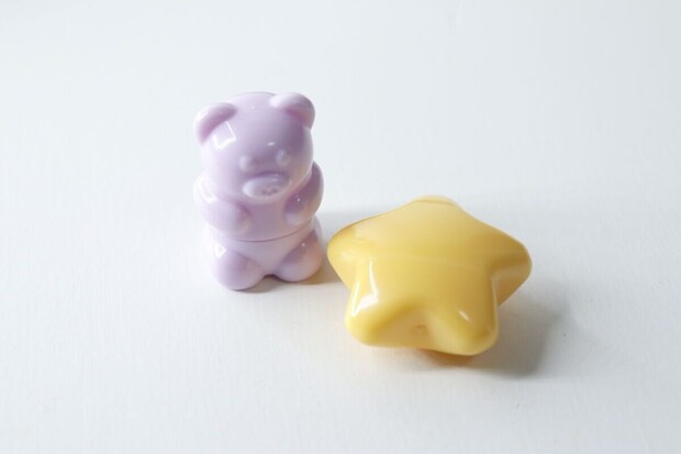 白い背景に置かれた、くまちゃん形と星形のミニリップブラシ(キャップ付き) 白い背景に置かれた、くまちゃん形と星形のミニリップブラシ(キャップ付き)