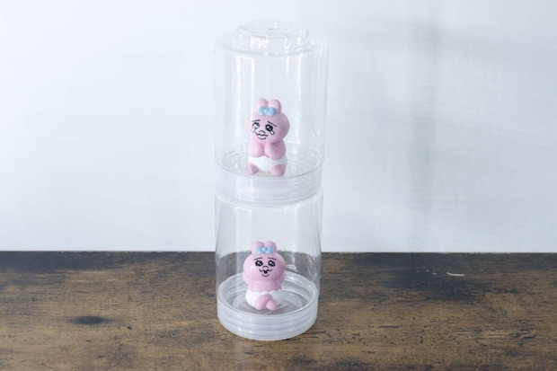 ピンクのフィギュアが入った円柱スタックケースが2つ縦に連結されている