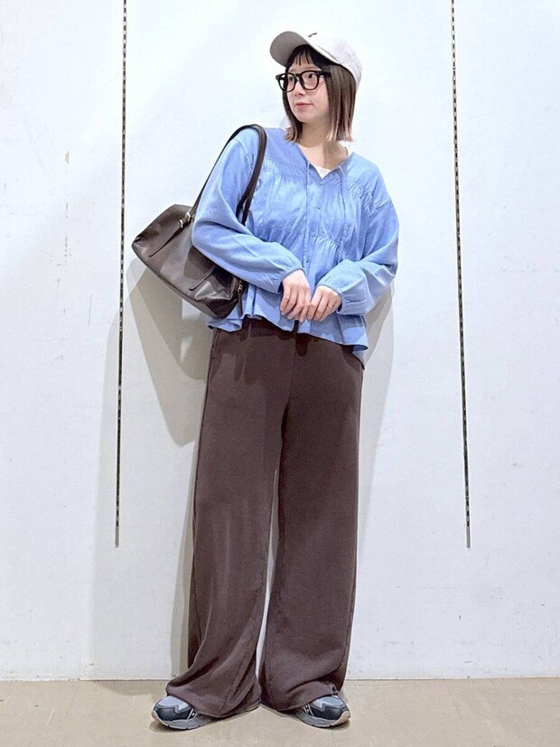 水色のシャーリングニットを着た女性がキャップとメガネで立つ 水色のシャーリングニットを着た女性がキャップとメガネで立つ