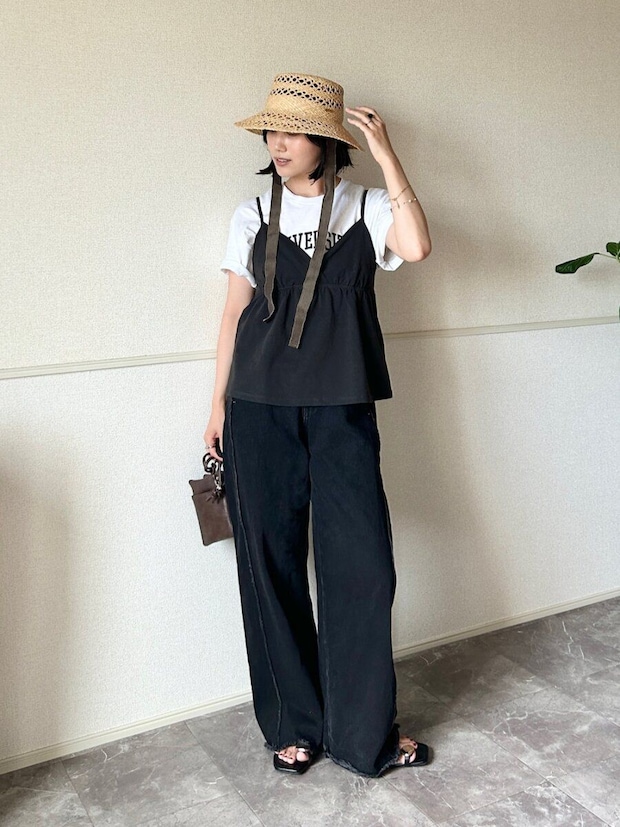 ロゴTシャツに黒キャミとワイドデニム、麦わら帽子を被った女性 ロゴTシャツに黒キャミとワイドデニム、麦わら帽子を被った女性