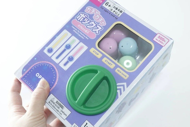 手がダイソーのガチャガチャボックスのパッケージを持つ