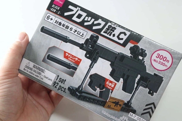 手がダイソーのブロック銃のパッケージを持つ