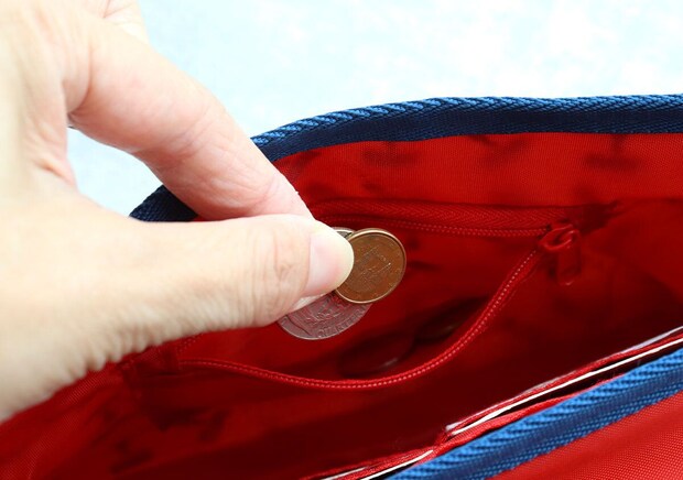 お財布ポシェットのファスナー付きポケットに硬貨を入れる手元