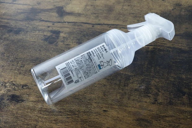透明なスプレー容器が木目のテーブルに斜めに置かれている