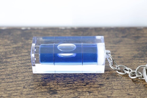 木目調の台に置かれたキーホルダー水平器を横から撮影