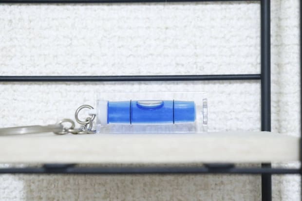 白い棚の縁に置かれたキーホルダー水平器 白い棚の縁に置かれたキーホルダー水平器