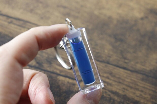 指でつまんで持っているキーホルダー水平器