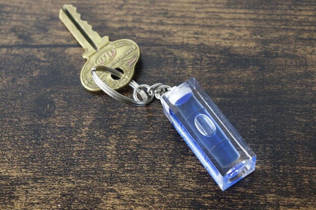 木目調の台に鍵とキーホルダー水平器が置かれている