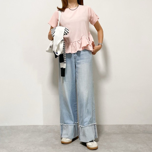 ピンクのペプラムトップスとデニムワイドパンツ、スニーカーのカジュアルコーデ。