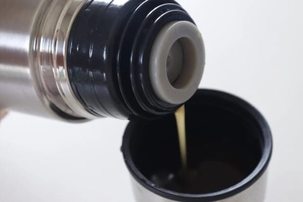 ステンレスボトルからカップにコーヒーのような液体を注いでいる