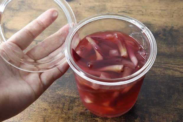 茗荷の甘酢漬けが入った容器の蓋を開けている手元 茗荷の甘酢漬けが入った容器の蓋を開けている手元
