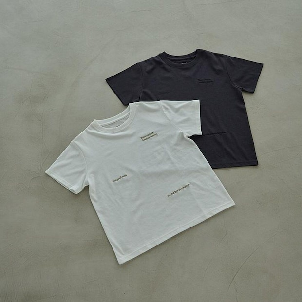 黒と白のロゴ入り半袖Tシャツが床に並べられている