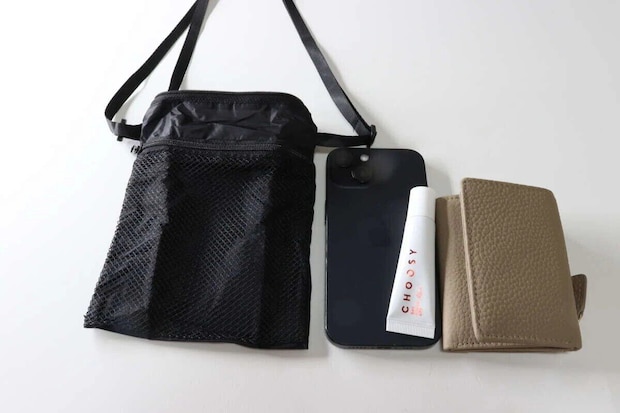黒いトラベルショルダーバッグと、スマホ、リップ、ミニ財布が並べられている 黒いトラベルショルダーバッグと、スマホ、リップ、ミニ財布が並べられている