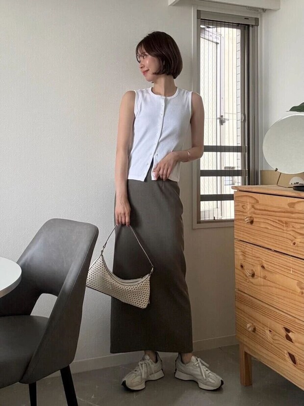 白いノースリーブとカーキのIラインスカートを着用し、白いバッグを持つ女性の全身 白いノースリーブとカーキのIラインスカートを着用し、白いバッグを持つ女性の全身