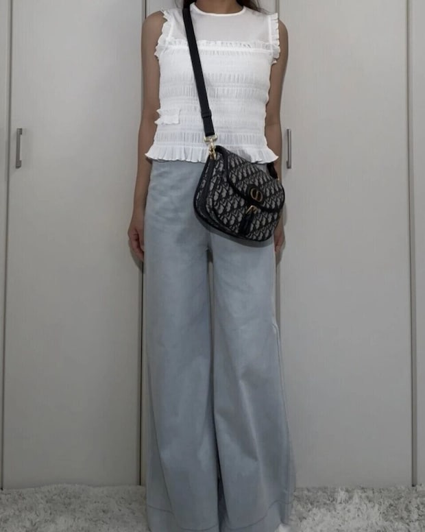 白いシャーリングノースリーブと薄いブルーのワイドデニムを着用した女性の全身