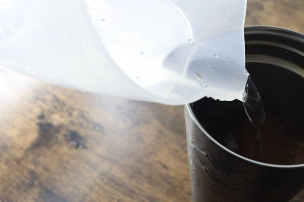 計量カップから黒いタンブラーへお湯を注いでいる様子