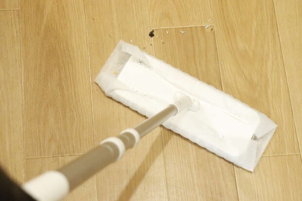 フローリングワイパーで床のほこりやゴミを掃除している様子