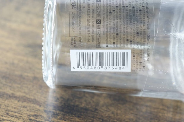 ガラス容器に貼られた商品情報シールの拡大。JANコードや使用上の注意が読み取れる。