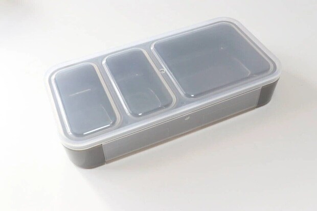 グレーの薄型弁当箱が上から写されており、透明な蓋から3つの仕切りが見える