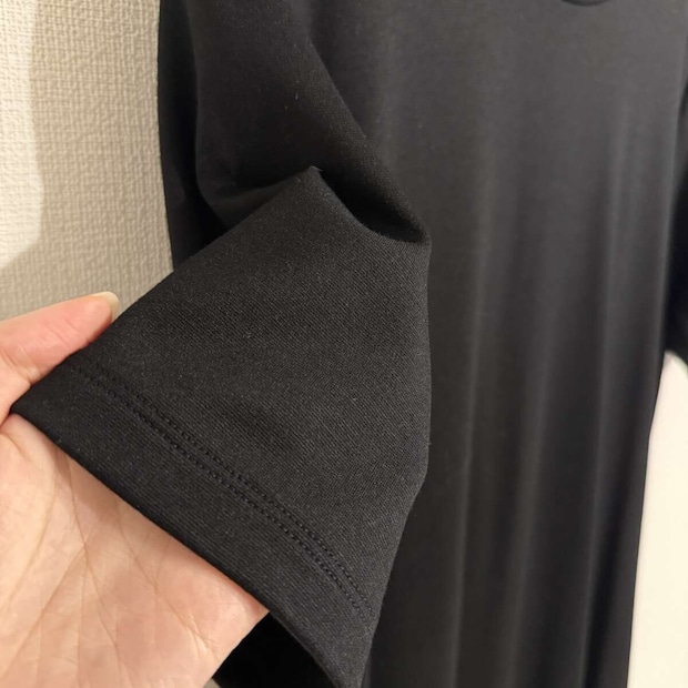手で黒いワンピースの袖口の生地感を見せている